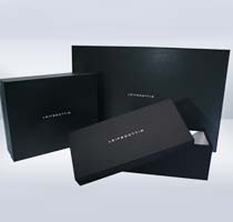 Three black gift boxes with the word INTERSECTION printed on them, arranged on a light background. One box is open, revealing a white interior, hinting at the elegance one might find in a pair of exquisite shoes.