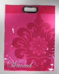 A pink glossy shopping bag with a large floral pattern and the word Wanted in elegant script at the bottom. Perfect for carrying your latest shoe purchase, it features a rectangular cut-out handle.