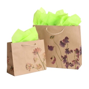 Two beige gift bags with floral designs, one larger with purple flowers and one smaller with pink flowers, both filled with bright green tissue paper, resemble elegant custom food packaging in their delightful presentation.