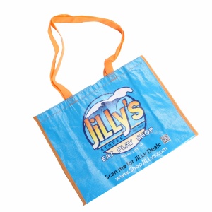 The blue and orange reusable shopping bag, made from ppnw material, features the text "Jillys Eat Play Shop" alongside a logo of waves. It includes a website link and QR code at the bottom, while vibrant orange handles are attached at the top.