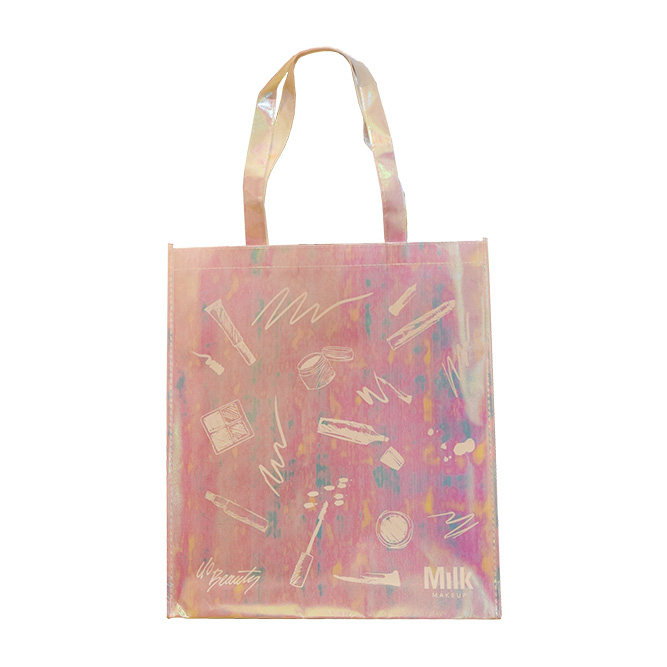 A holographic tote bag with makeup illustrations, including brushes, lipstick, and compact. The bag has translucent handles and displays the word Milk along with various artistic designs.
