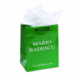 A stylish green shopping bag with black handles features the text Mario Badescu and subtle embellishments. White tissue paper is elegantly peeking out of the top, adding a touch of sophistication.