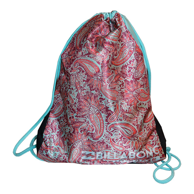 A drawstring bag with a vibrant red and white paisley design and Billabong printed at the bottom. The bag features light blue drawstrings and trim, with black accents on the sides.