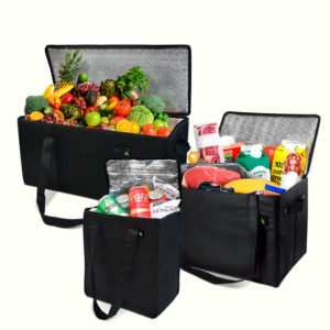 Three black reusable grocery bags brim with various items. One bag flaunts fresh fruits and vegetables, another cradles beverages and canned goods, while the third is laden with take away packaging alongside packaged foods and snacks. Each bag stands open, revealing its bounty.