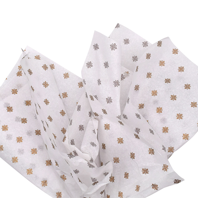 Crumpled white tissue paper with a repeating pattern of small golden and brown geometric designs.