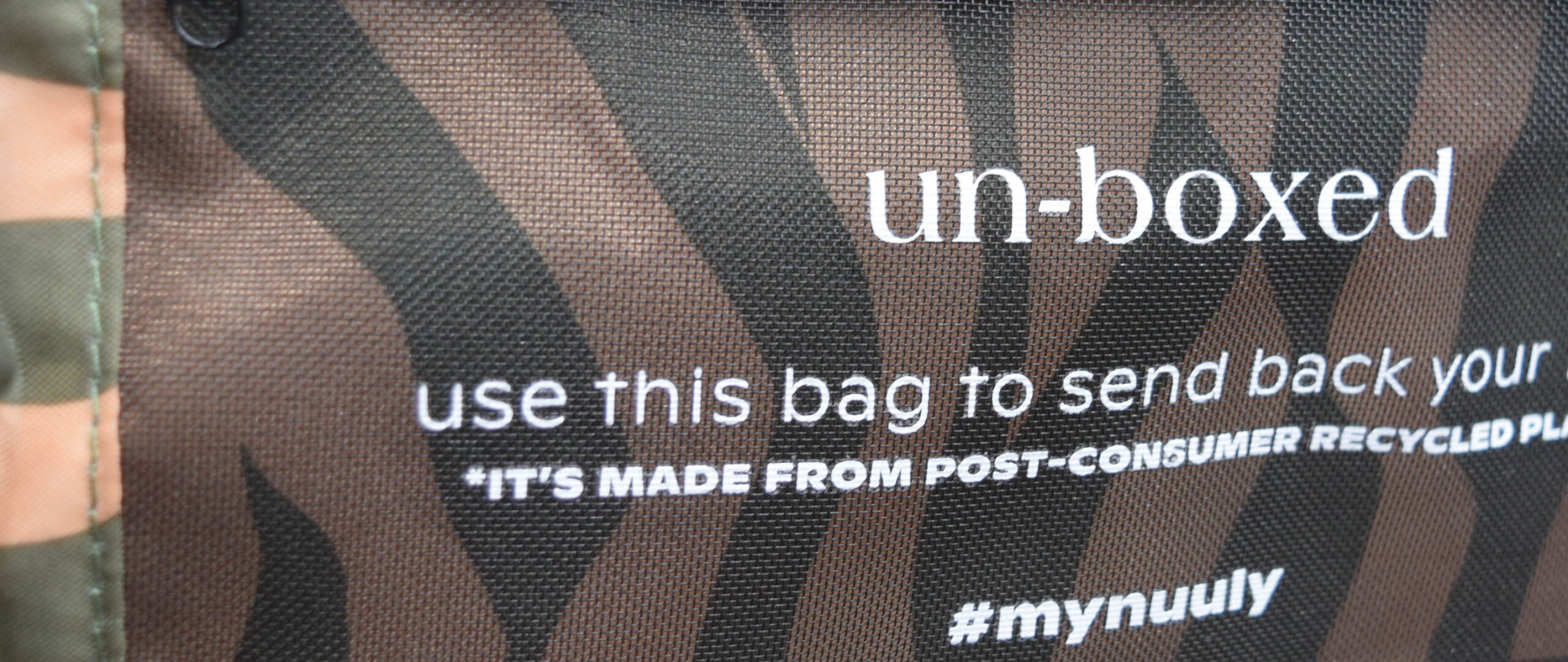 Close-up of a bag with a zebra print pattern. Text on the bag reads: un-boxed, use this NUULY subscription box to send back your *its made from post-consumer recycled pl..., followed by #mynuuly.